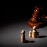 Wooden toy family and judge mallet close up. Family divorce concept